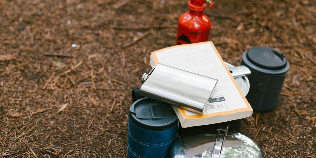 flat lay photography of hip flask, book, tiffin carrier and container