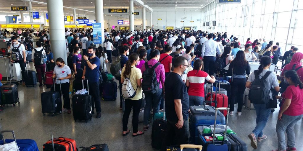 Crowded Bangkok airport terminal with travelers and luggage.